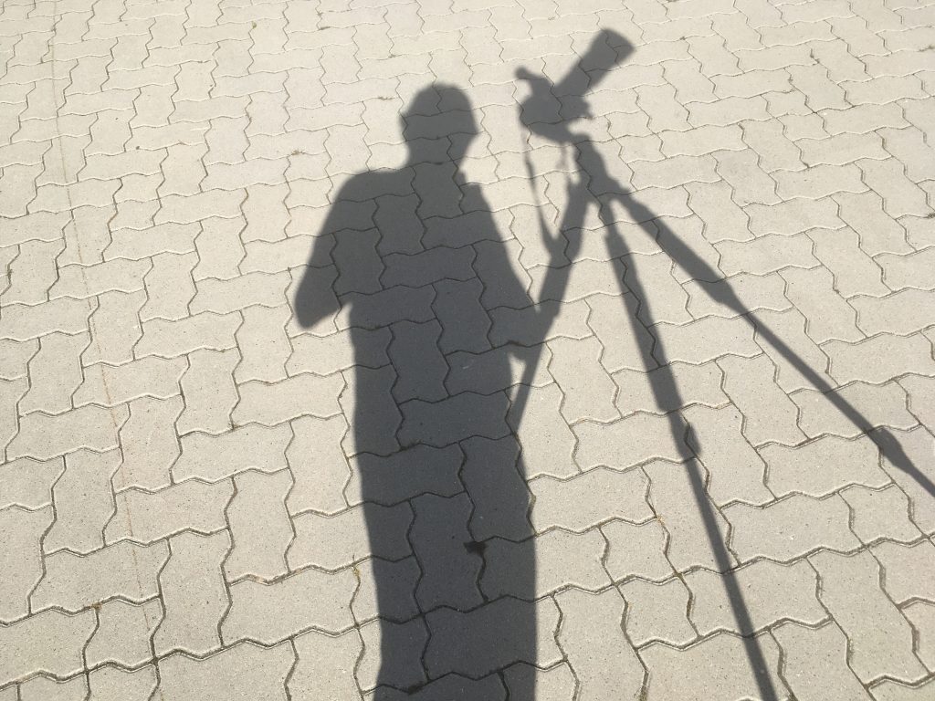 Der Schatten einer Person an einem Stativ mit Fotoapparat.